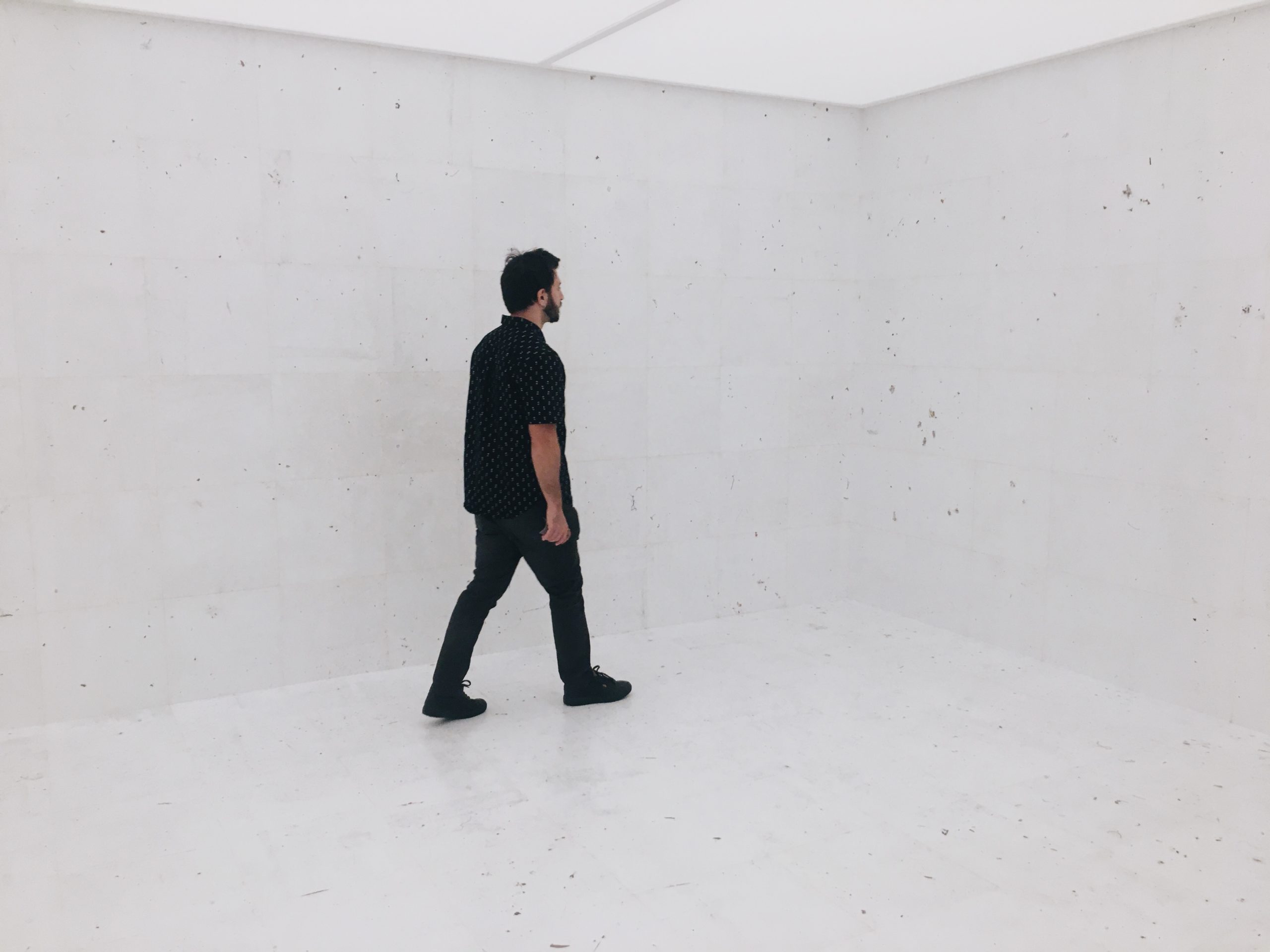 Man walking in white room towards corner.